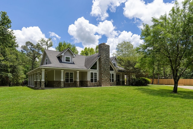 back of property featuring a lawn, fence, stone siding, and a chimney