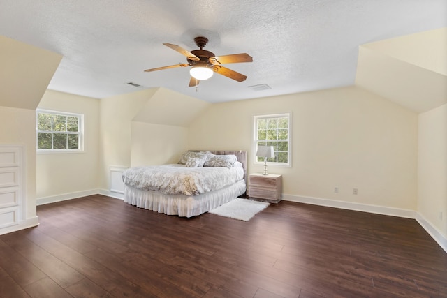 bedroom with vaulted ceiling, dark wood-style floors, and visible vents