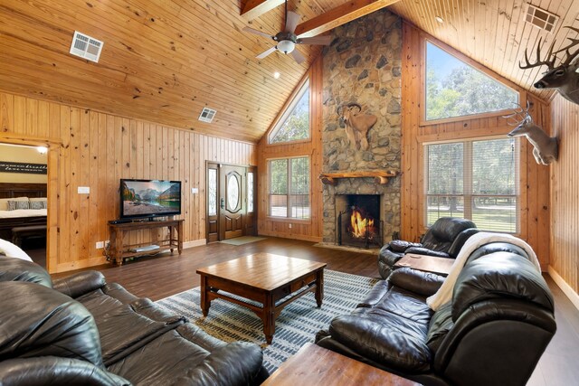 living room with a fireplace, wood finished floors, visible vents, and wood walls