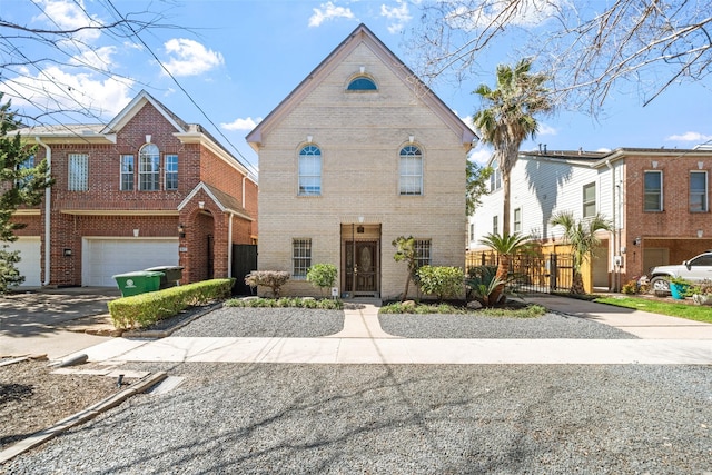 traditional home with an attached garage, brick siding, fence, driveway, and a gate