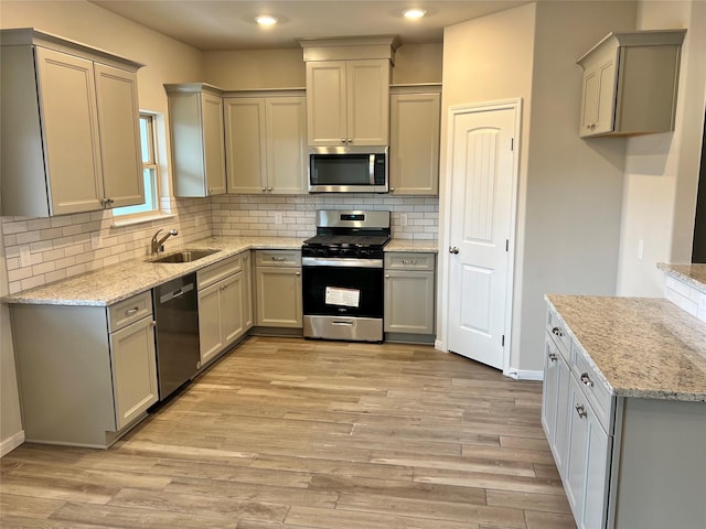 kitchen with appliances with stainless steel finishes, gray cabinets, and a sink