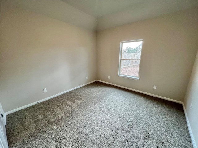 spare room featuring dark colored carpet and baseboards