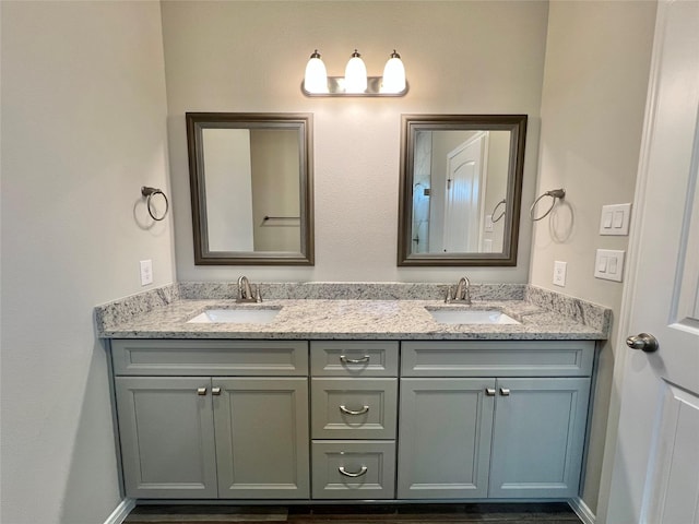 full bathroom featuring a sink, baseboards, and double vanity