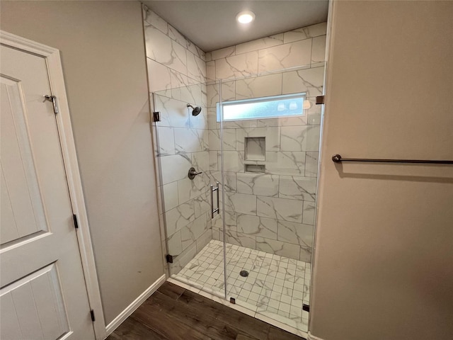 full bathroom with a stall shower, baseboards, and wood finished floors