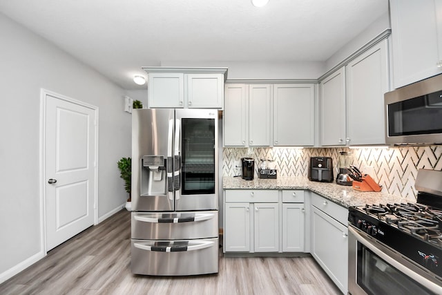 kitchen featuring appliances with stainless steel finishes, backsplash, and light wood-style floors