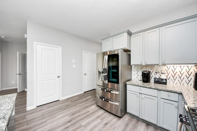 kitchen featuring gray cabinetry, stainless steel appliances, light wood-style flooring, and decorative backsplash