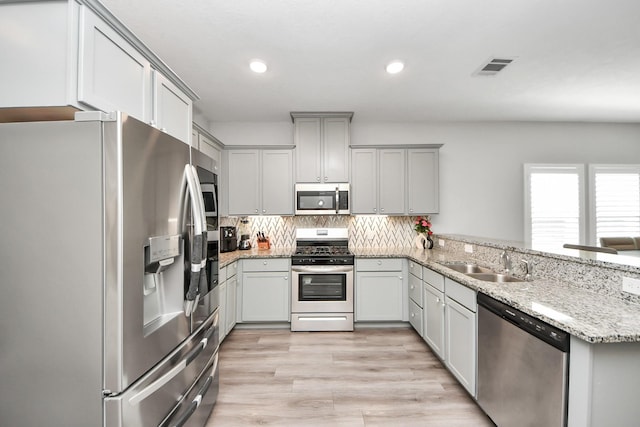 kitchen with stainless steel appliances, gray cabinets, visible vents, decorative backsplash, and a sink