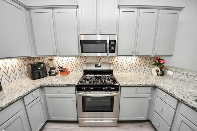 kitchen with stainless steel appliances, gray cabinetry, and tasteful backsplash