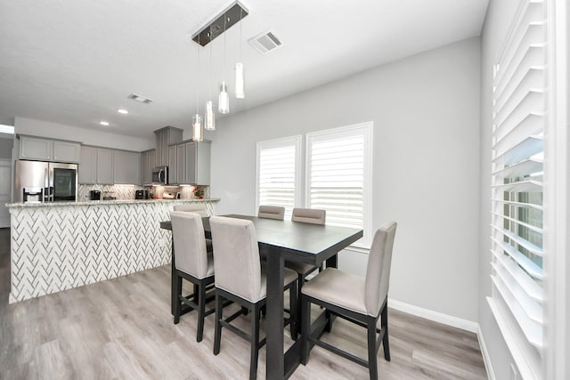 dining area featuring light wood-style floors, baseboards, and visible vents