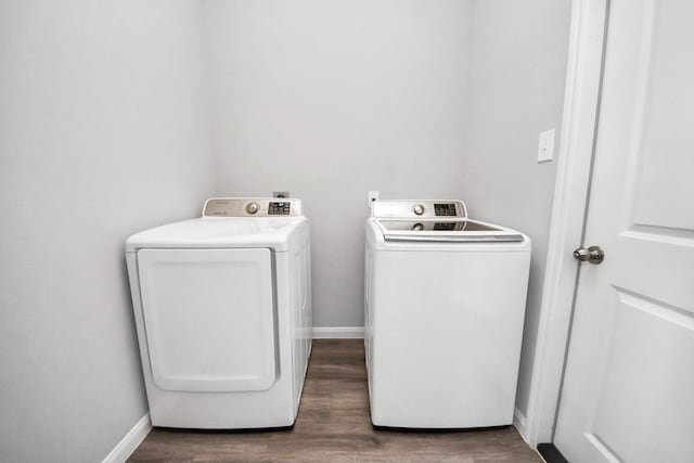 washroom featuring laundry area, wood finished floors, washing machine and clothes dryer, and baseboards