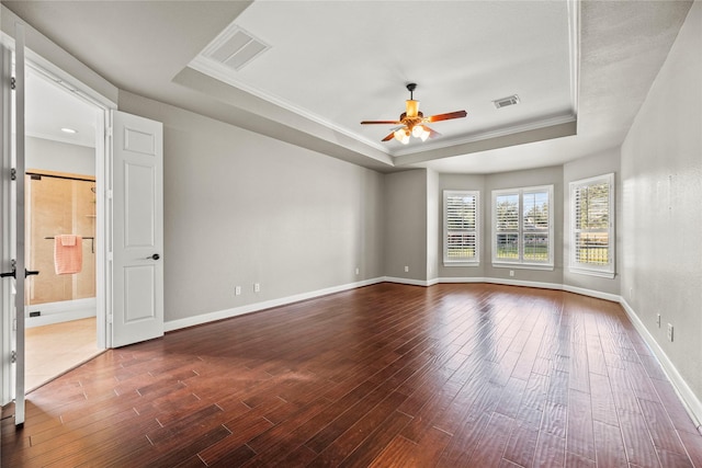 spare room with a raised ceiling, visible vents, and dark wood finished floors