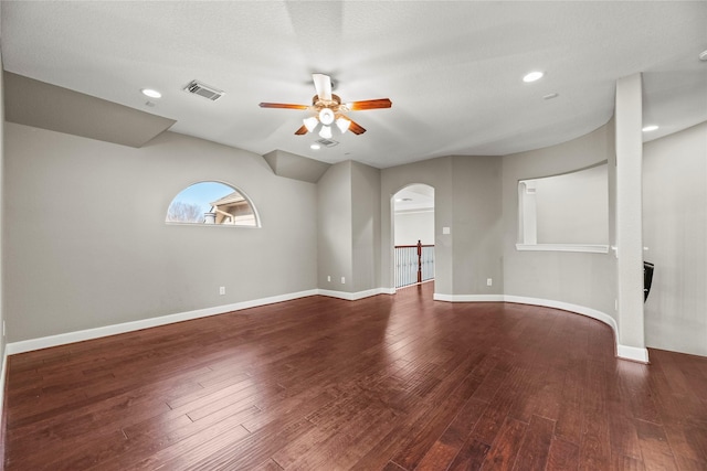 unfurnished room featuring arched walkways, visible vents, ceiling fan, baseboards, and hardwood / wood-style flooring