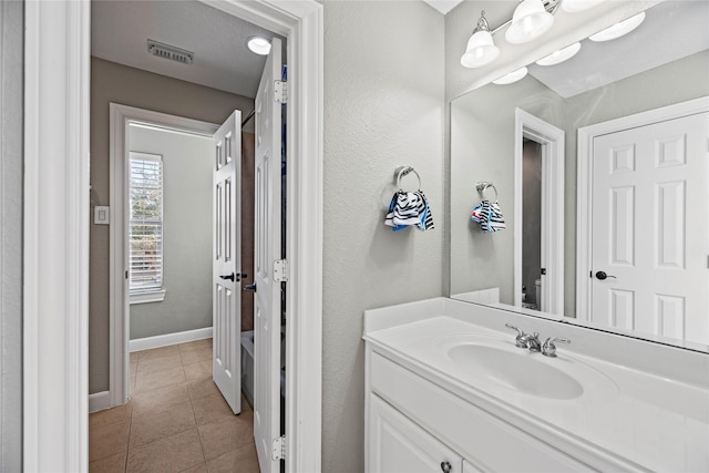 bathroom with baseboards, vanity, visible vents, and tile patterned floors