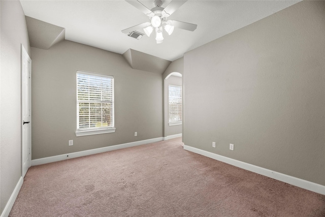 carpeted spare room with arched walkways, visible vents, vaulted ceiling, ceiling fan, and baseboards