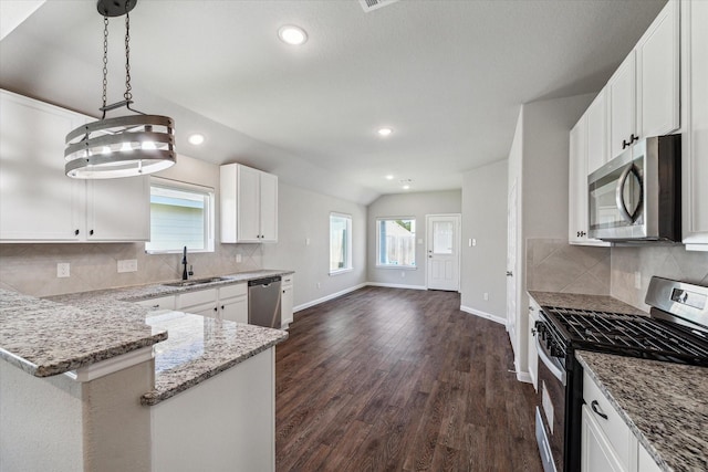 kitchen with dark wood-type flooring, light stone countertops, lofted ceiling, appliances with stainless steel finishes, and a sink