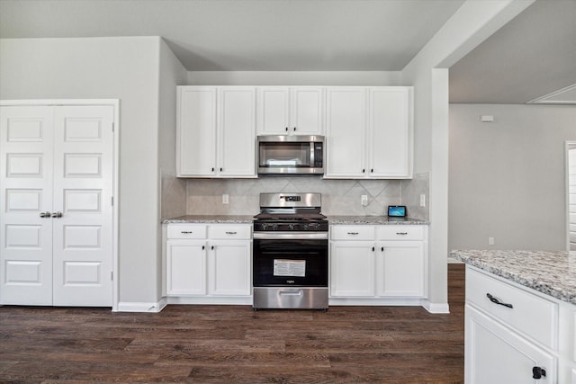 kitchen featuring light stone counters, dark wood finished floors, white cabinets, appliances with stainless steel finishes, and tasteful backsplash