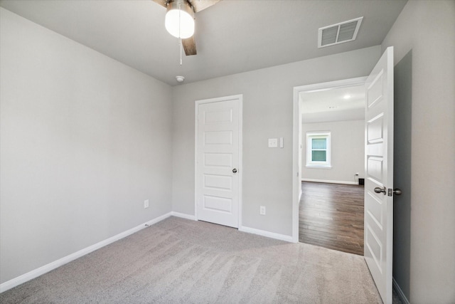 unfurnished bedroom featuring visible vents, a ceiling fan, baseboards, and dark colored carpet