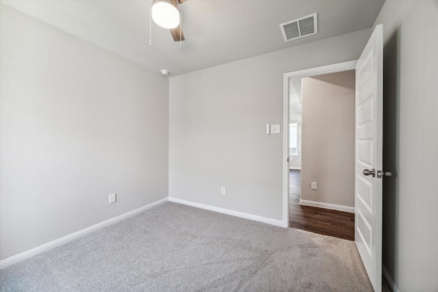 spare room with dark colored carpet, visible vents, baseboards, and ceiling fan