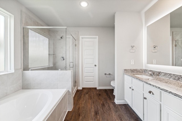 bathroom featuring vanity, wood finished floors, a stall shower, a garden tub, and toilet