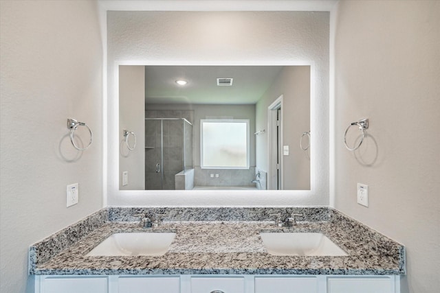 bathroom featuring double vanity, visible vents, a shower stall, and a sink