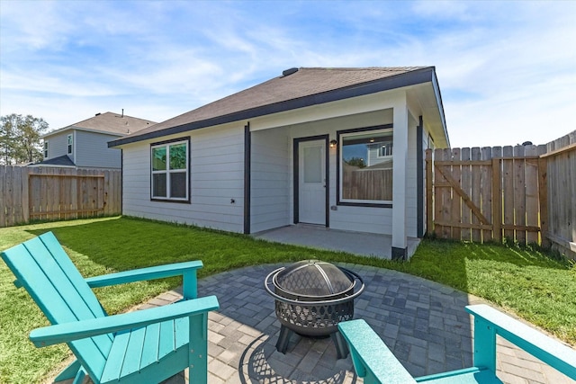 rear view of property featuring a fire pit, a fenced backyard, a yard, a patio, and a gate