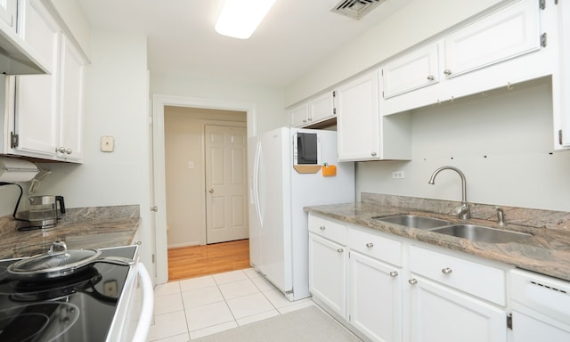 kitchen featuring light tile patterned floors, a sink, and white cabinets