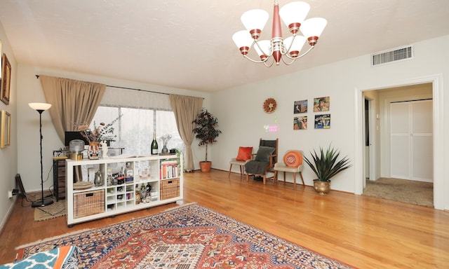 sitting room featuring a notable chandelier, visible vents, and wood finished floors