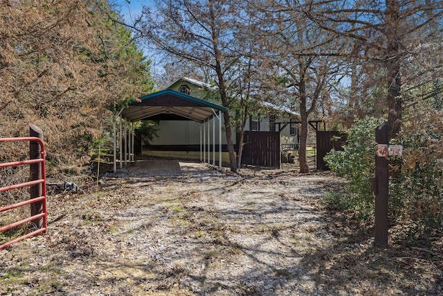 view of yard featuring a detached carport, driveway, and fence