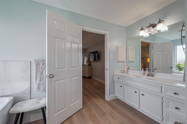 full bath featuring a soaking tub, baseboards, wood finished floors, and vanity