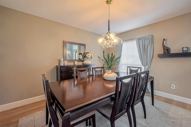 dining space with light wood finished floors, baseboards, and an inviting chandelier