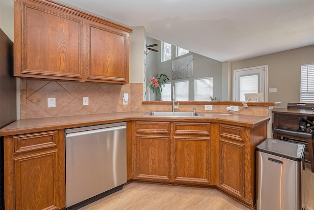 9314 Dune Gate Ct, Humble, TX 77396 - kitchen with stainless steel dishwasher, brown cabinetry, a peninsula, ceiling fan, and light wood-type flooring