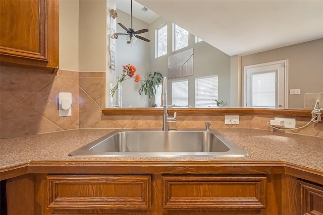 kitchen with ceiling fan, brown cabinetry, and a sink