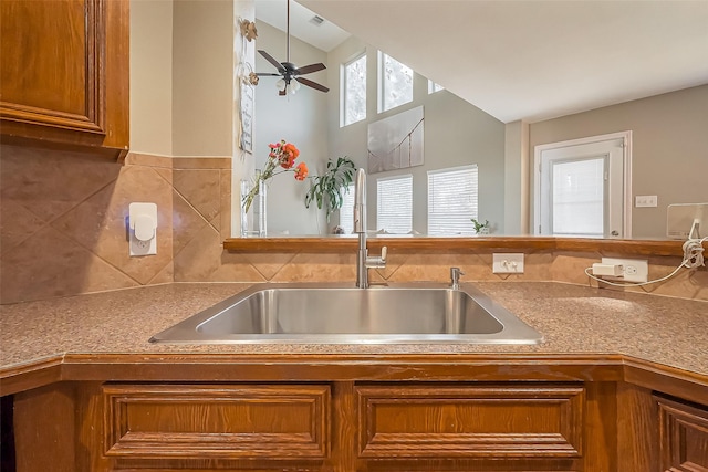 9314 Dune Gate Ct, Humble, TX 77396 - kitchen with brown cabinetry, vaulted ceiling, decorative backsplash, and a ceiling fan
