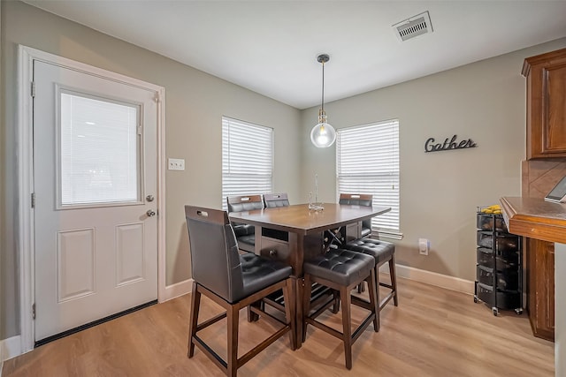 dining area featuring light wood finished floors, baseboards, and visible vents