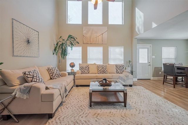 living area featuring a towering ceiling, baseboards, and wood finished floors