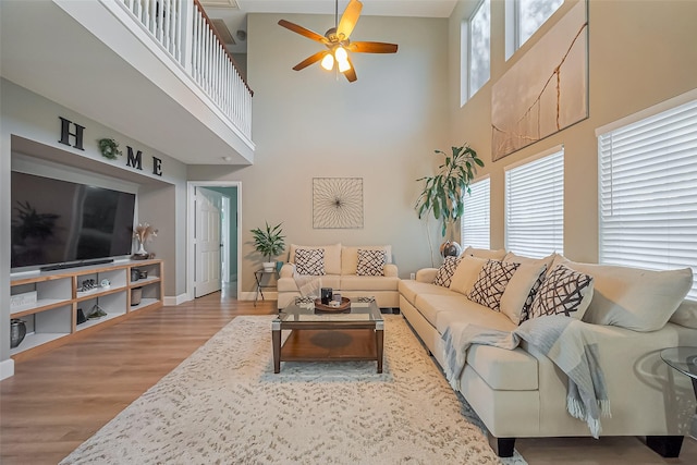 living area with baseboards, a ceiling fan, and wood finished floors