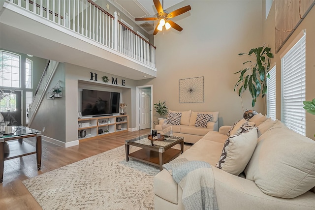 living area featuring a high ceiling, baseboards, and wood finished floors