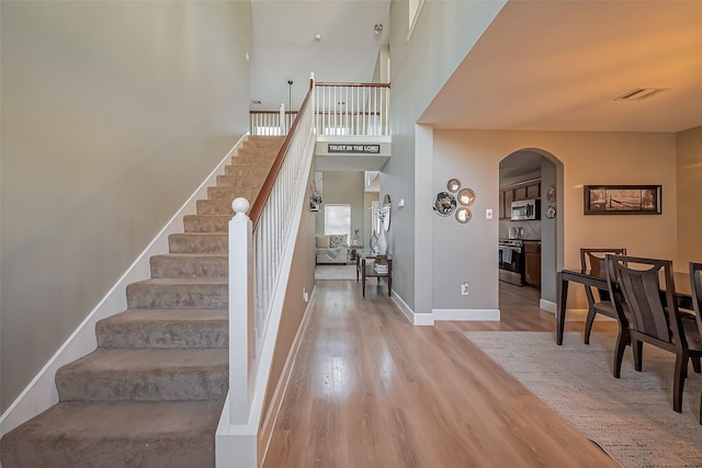 9314 Dune Gate Ct, Humble, TX 77396 - stairs featuring arched walkways, wood finished floors, and a high ceiling