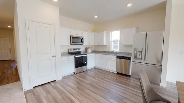 kitchen with light wood-style flooring, light stone countertops, stainless steel appliances, white cabinetry, and recessed lighting