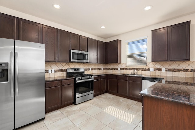 kitchen with appliances with stainless steel finishes, dark stone countertops, backsplash, and dark brown cabinetry