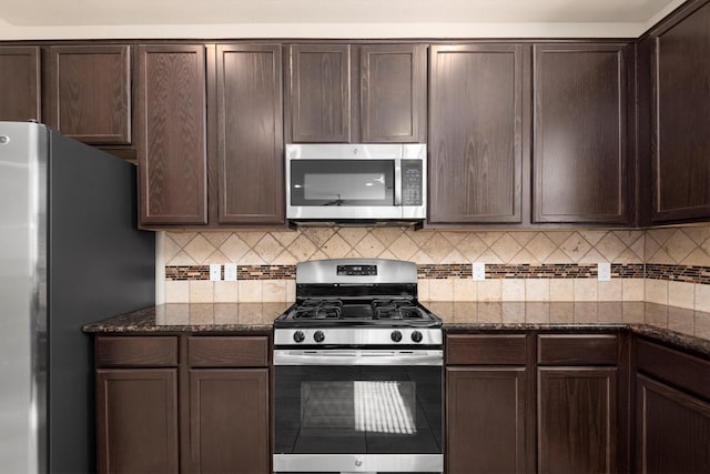 kitchen with dark stone counters, stainless steel appliances, and dark brown cabinets