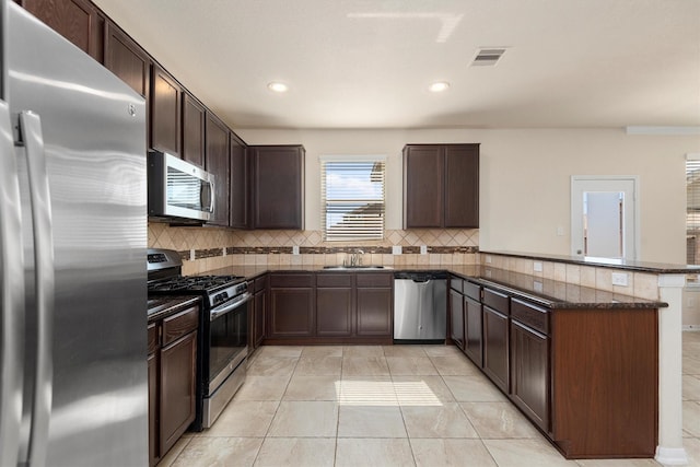 kitchen featuring tasteful backsplash, visible vents, a peninsula, stainless steel appliances, and dark brown cabinets