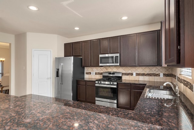 kitchen with appliances with stainless steel finishes, a sink, dark brown cabinets, backsplash, and recessed lighting