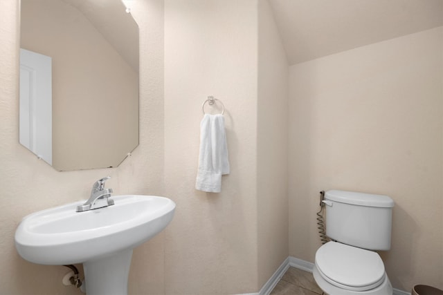 bathroom with toilet, baseboards, and tile patterned floors