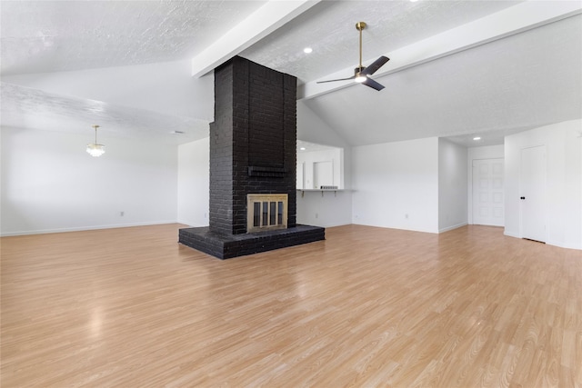 unfurnished living room with a textured ceiling, a fireplace, a ceiling fan, light wood-style floors, and beam ceiling