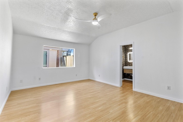 spare room featuring ceiling fan, a textured ceiling, baseboards, vaulted ceiling, and light wood finished floors