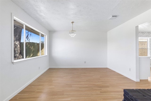 spare room with visible vents, plenty of natural light, and light wood finished floors