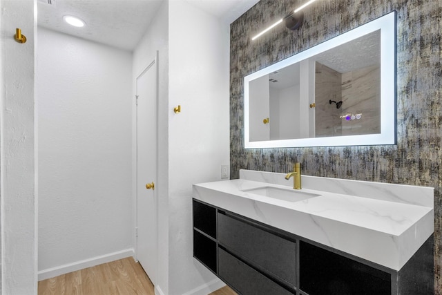 bathroom with wood finished floors, vanity, and baseboards