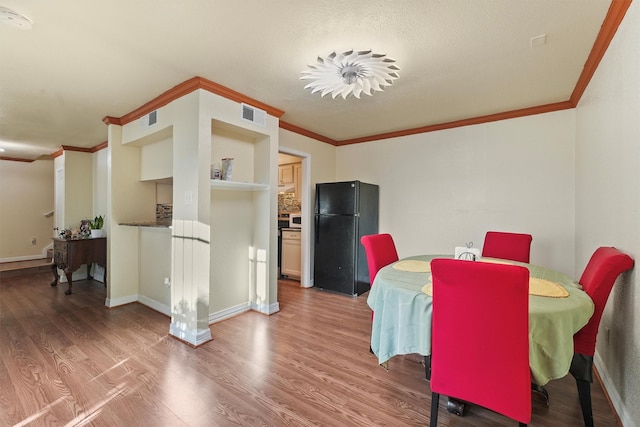 dining area with visible vents, wood finished floors, and ornamental molding