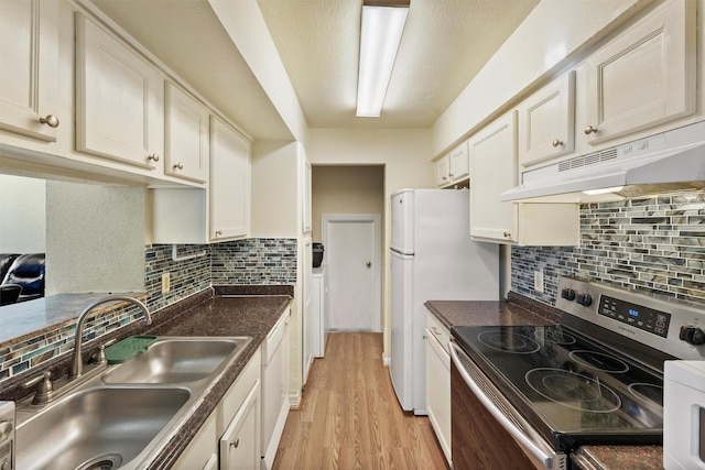 kitchen with dark countertops, light wood-style flooring, a sink, white appliances, and under cabinet range hood